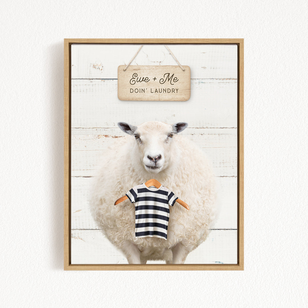 A framed image of a sheep wearing a striped shirt, with a sign above it that says "Eue + Me Doin' Laundry".
