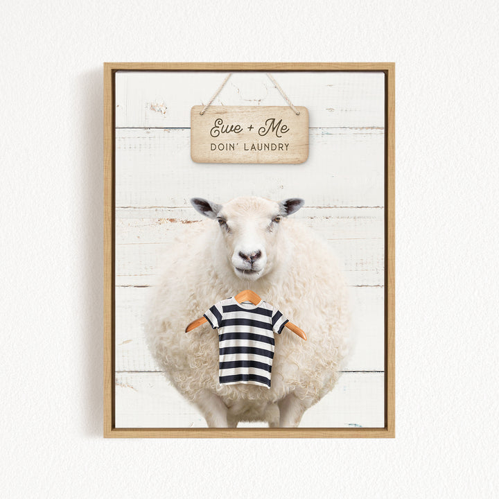A framed image of a sheep wearing a striped shirt, with a sign above it that says "Eue + Me Doin' Laundry".