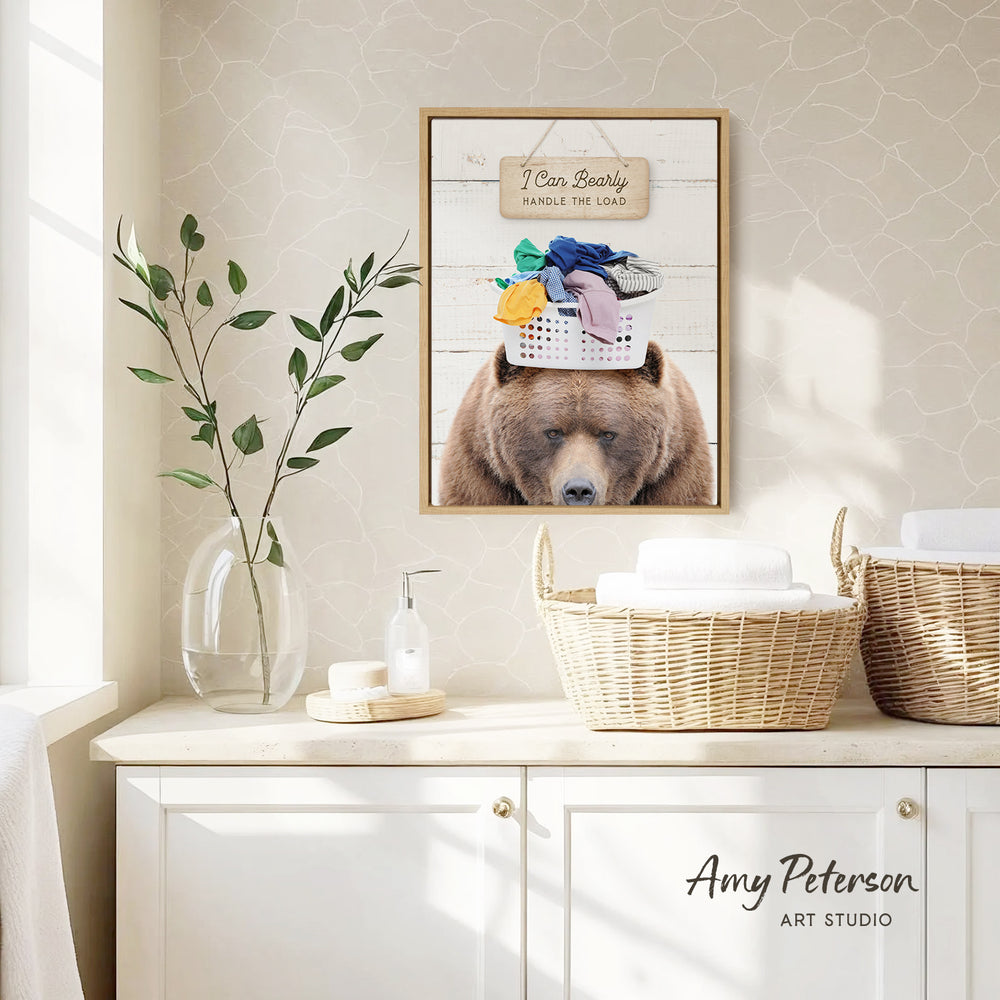 a framed picture of a bear with a laundry basket on its head, hanging on a wall above a white cabinet.