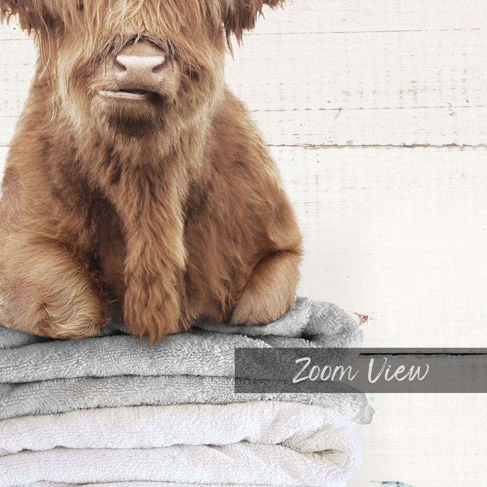 A close-up of a furry brown animal, possibly a yak or a similar animal, sitting on top of a stack of towels.