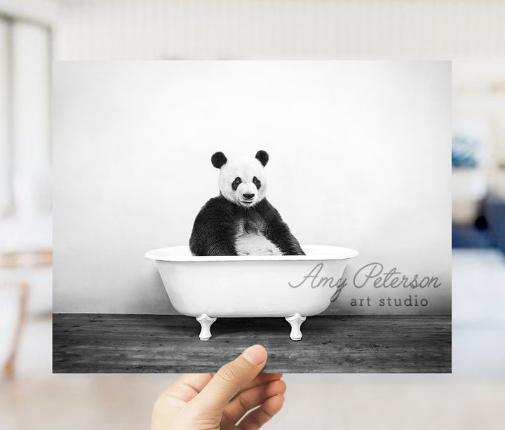 a person holding up a black and white photo of a panda in a bathtub