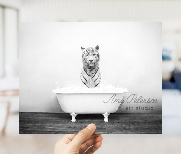 a hand holding up a black and white photo of a tiger in a bathtub