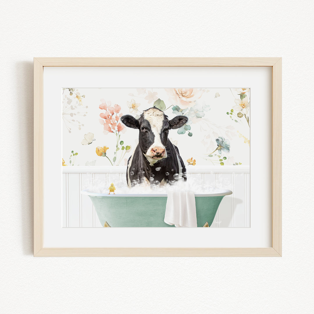 A black and white cow is sitting in a green bathtub filled with bubbles, surrounded by a floral background.