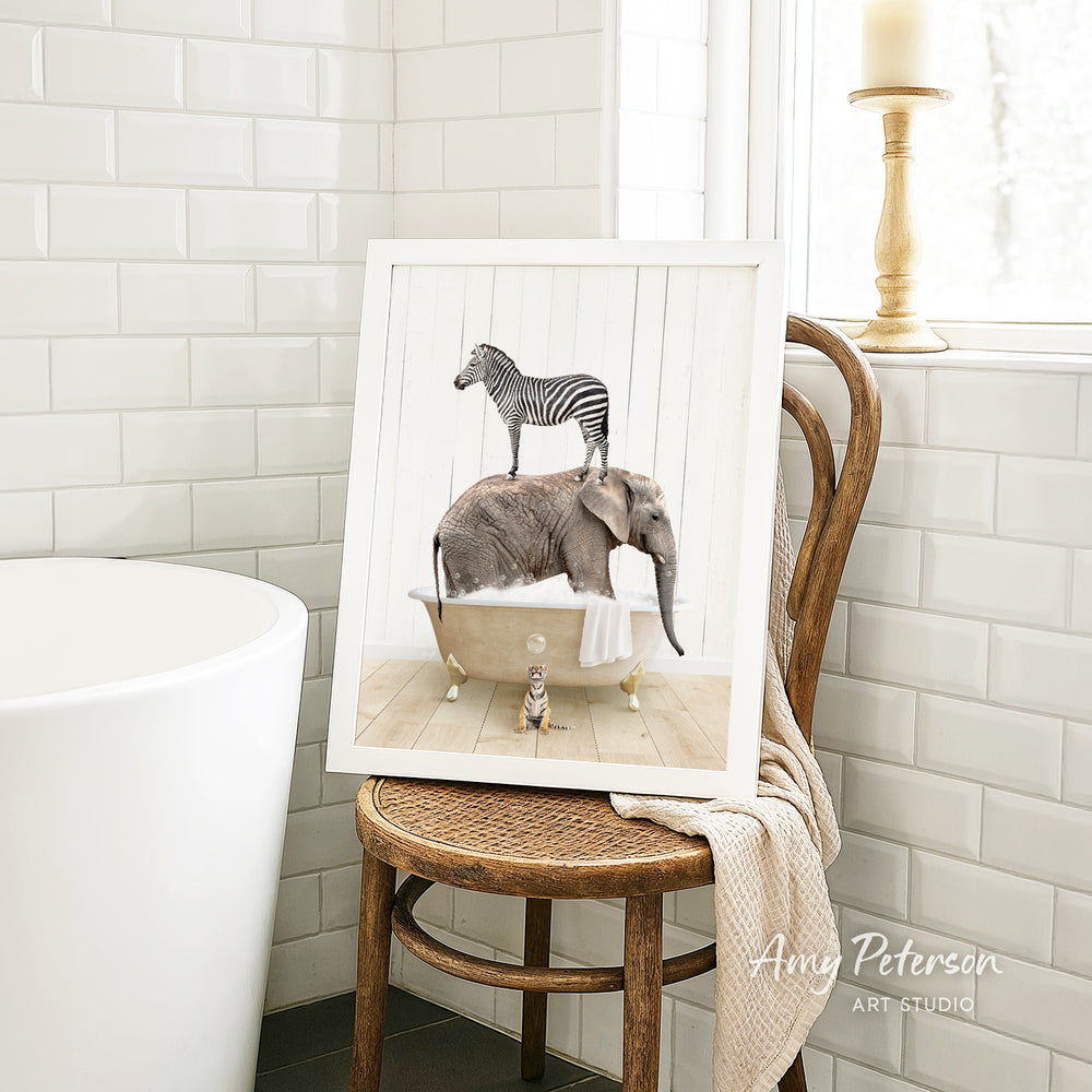 A framed image of a zebra standing on an elephant's back while the elephant is in a bathtub, with a towel draped over the chair.