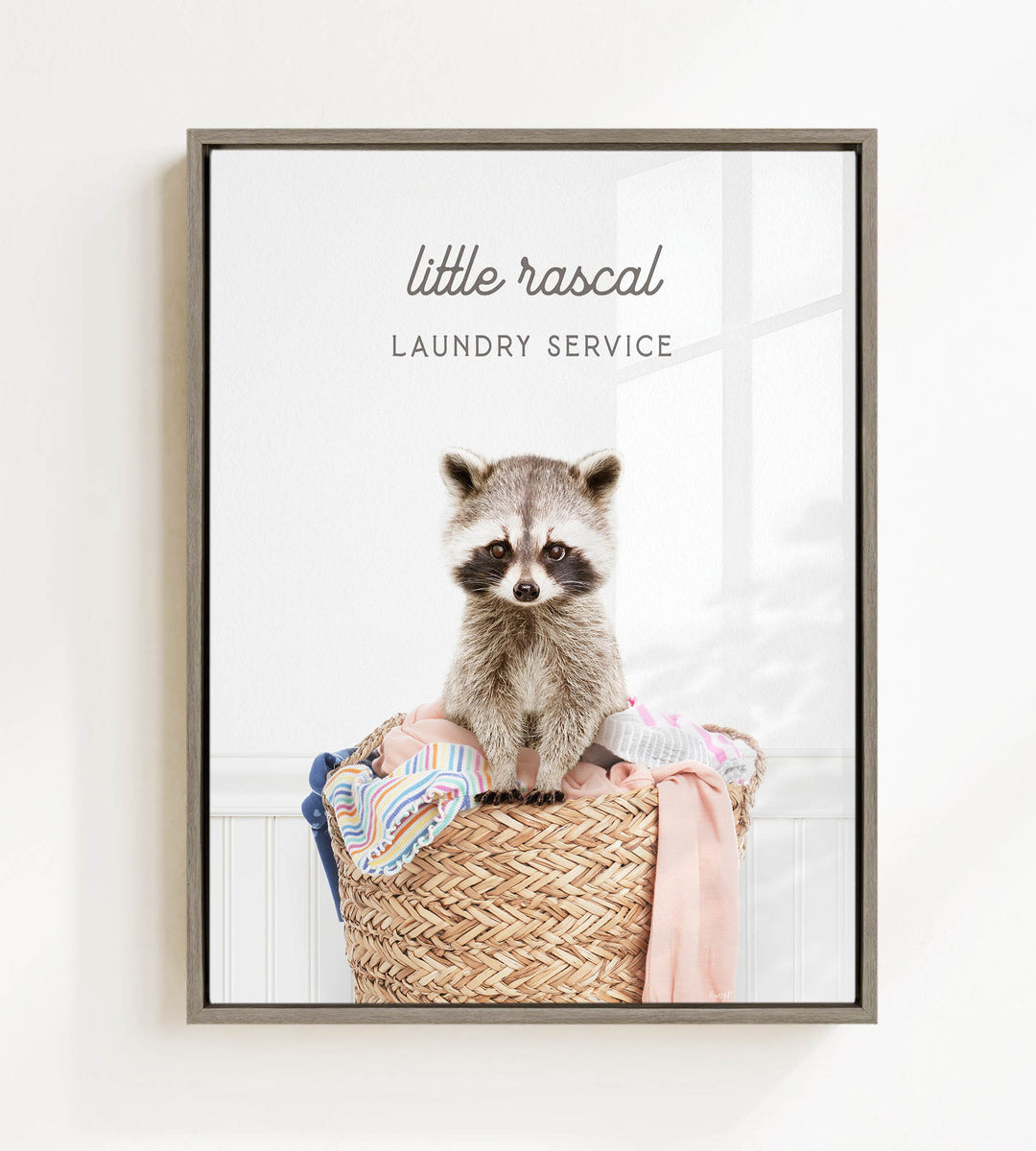 A raccoon sitting in a woven laundry basket, with the text "little raccal Laundry Service" displayed above the image.
