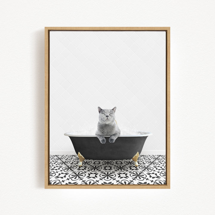 A gray cat sitting in a black bathtub filled with bubbles, surrounded by a black and white patterned floor.