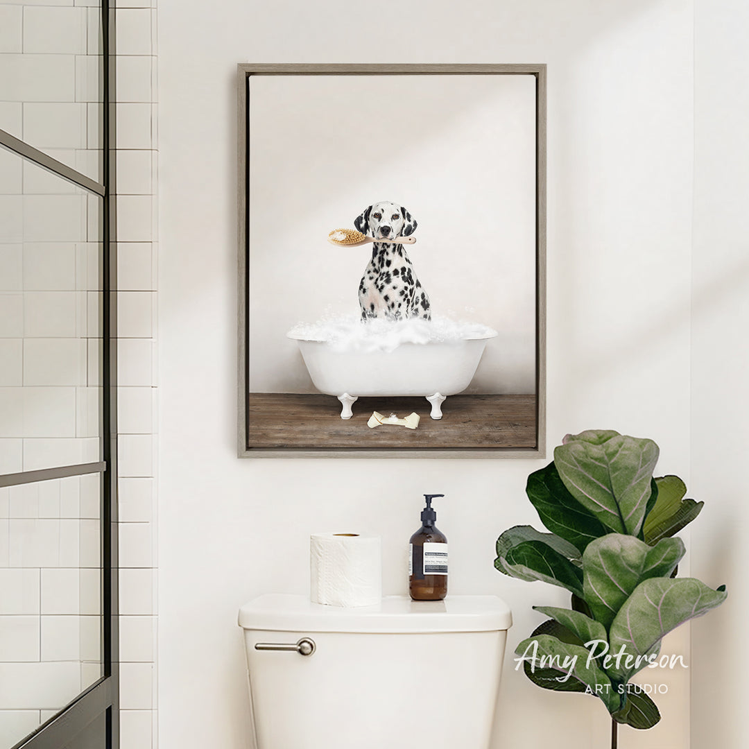 A framed image of a Dalmatian dog sitting in a bathtub, with a towel and a bottle of soap on the toilet tank.