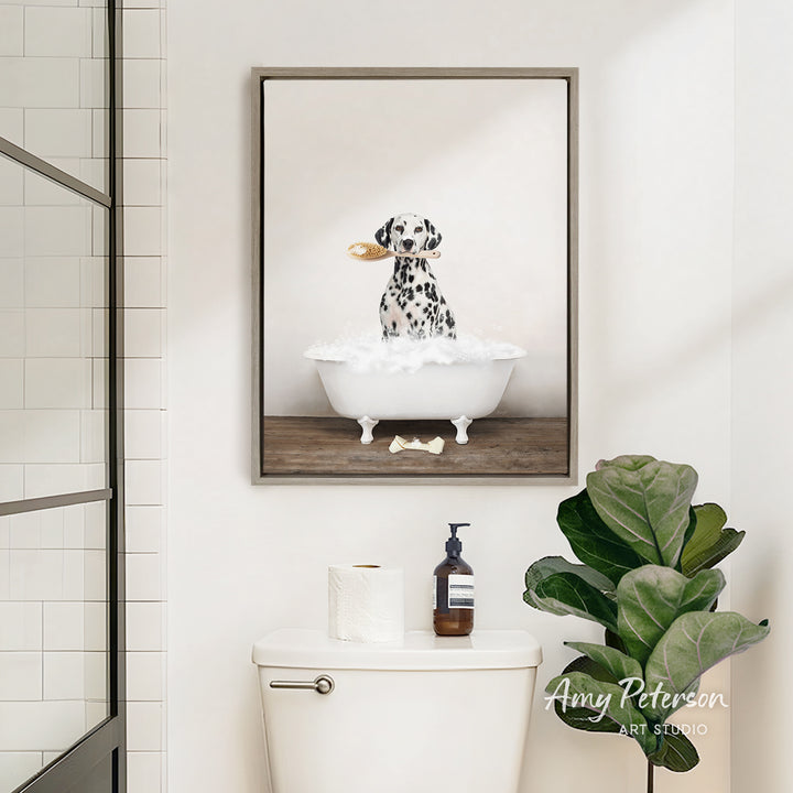A framed image of a Dalmatian dog sitting in a bathtub, with a towel and a bottle of soap on the toilet tank.