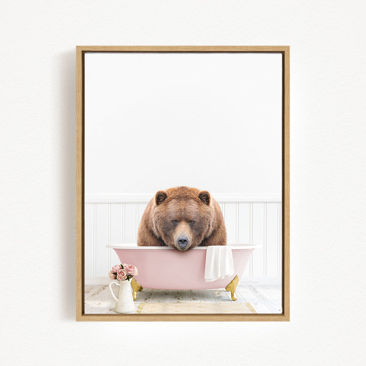A brown bear is sitting in a pink bathtub, surrounded by flowers and a white vase, creating a whimsical and charming scene.