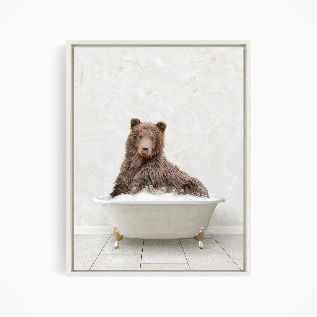 A brown bear sitting in a white bathtub filled with water, looking directly at the camera.