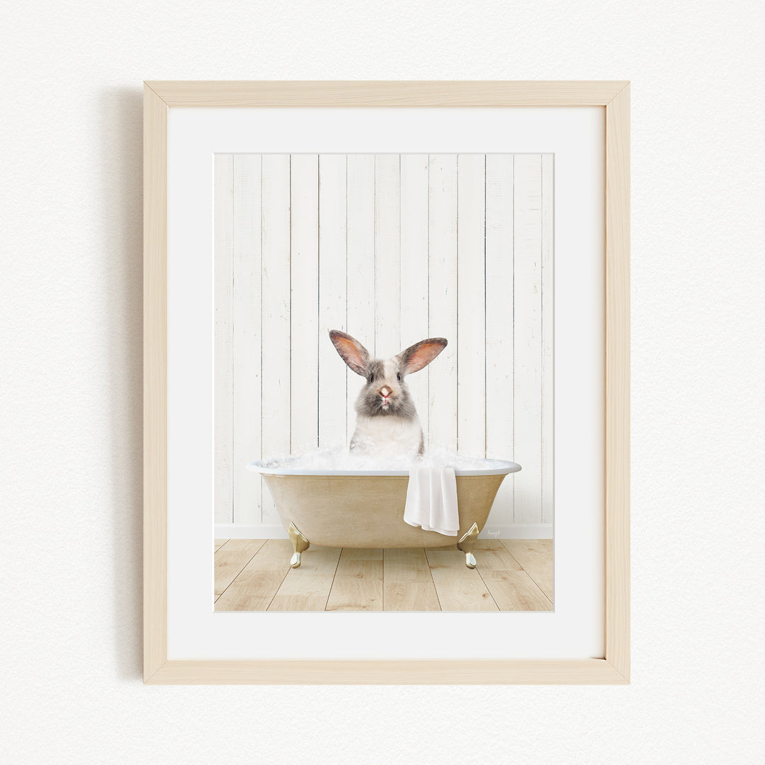 A small rabbit sitting in a bathtub filled with water, with a towel draped over the side of the tub.