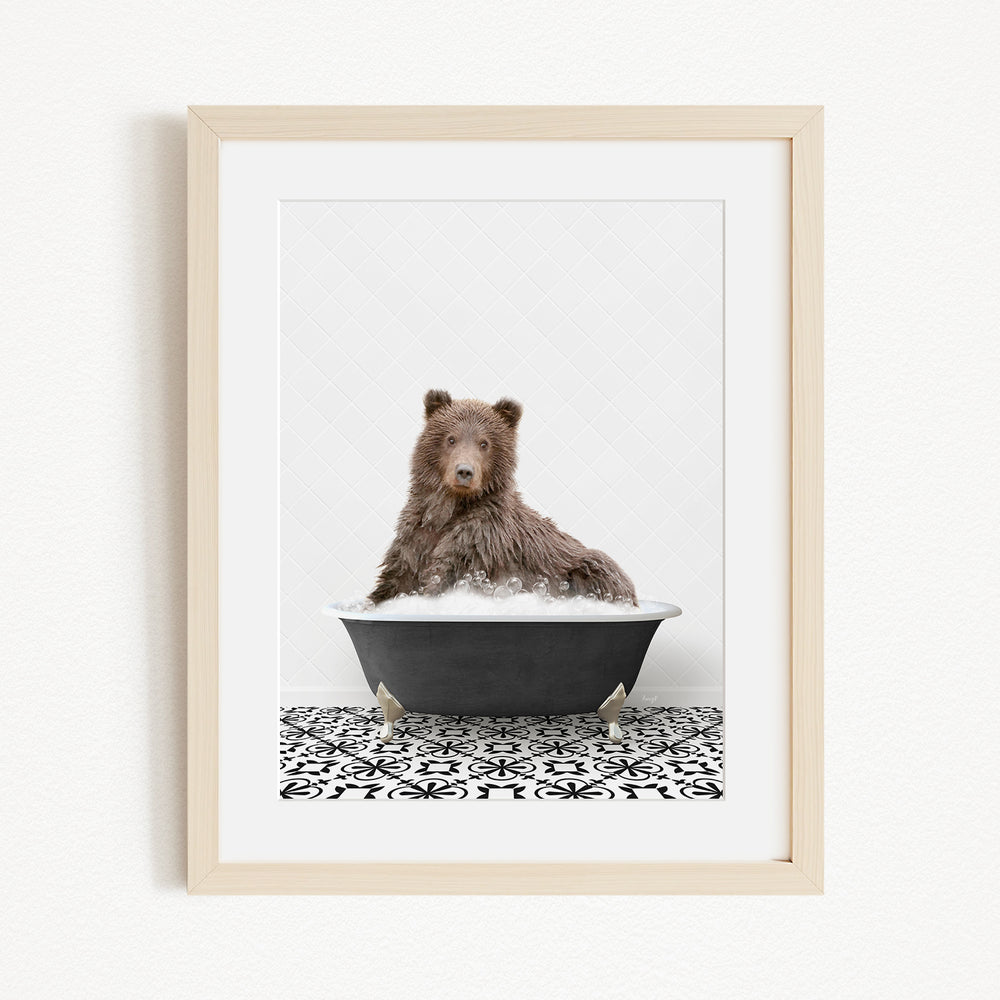 A brown bear sitting in a black bathtub filled with bubbles, surrounded by a black and white patterned floor.