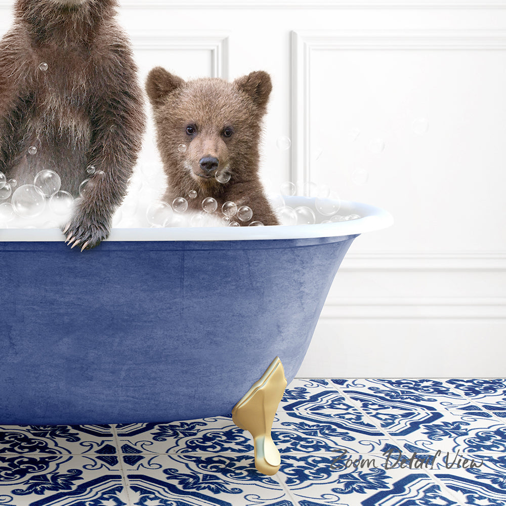 A baby bear sitting in a blue bathtub, surrounded by bubbles, with a gold claw-like object on the floor.