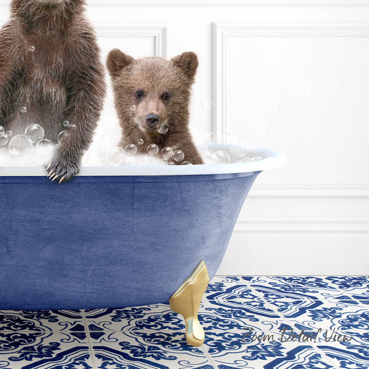 A baby bear sitting in a blue bathtub, surrounded by bubbles, with a gold claw-like object on the floor.