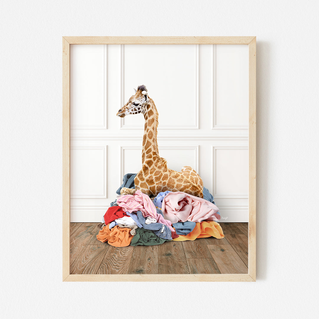 a giraffe sitting on top of a pile of clothes