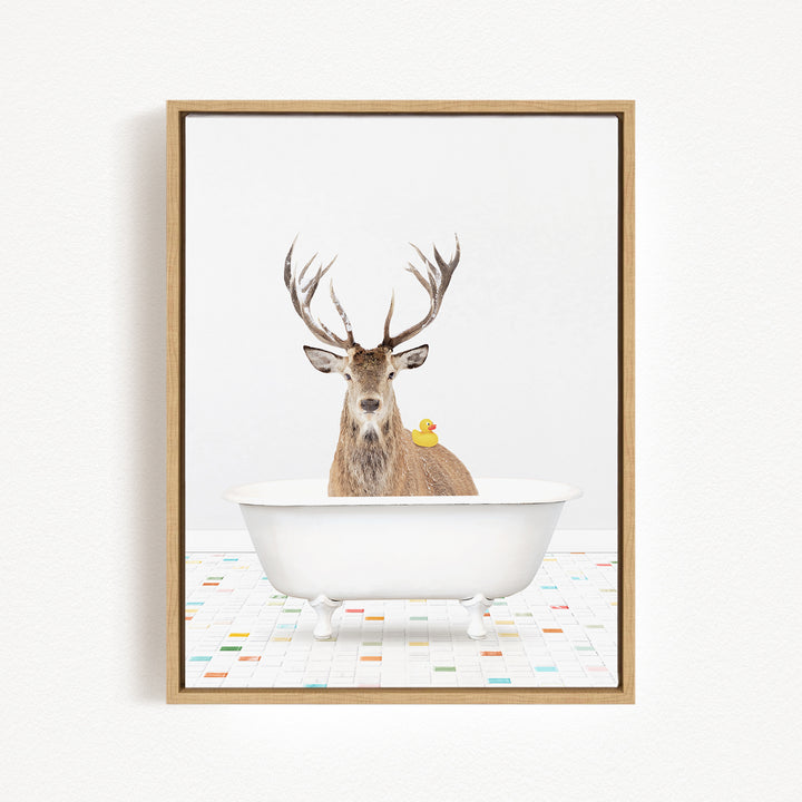 A deer with antlers is sitting in a white bathtub, with a rubber duck perched on its back.