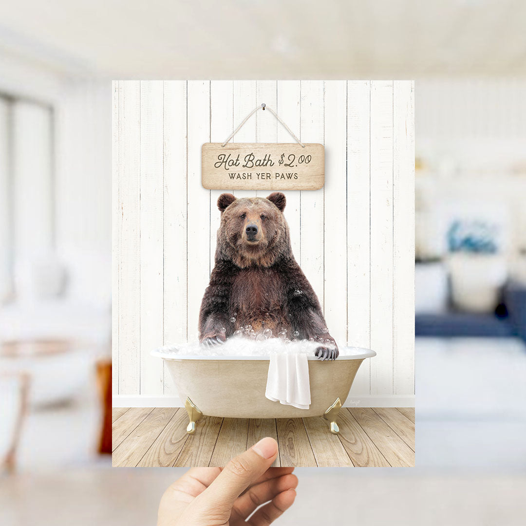 A brown bear sitting in a bathtub, with a sign above it that says "Hot Bath $2.00 WASH YER Paws".