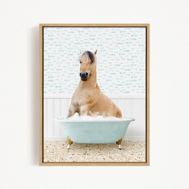 A light brown horse is sitting in a light blue bathtub filled with water, surrounded by a pattern of small fish on the wall behind it.
