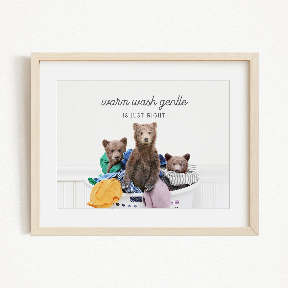 A framed image depicting three bears sitting in a laundry basket, with the text "Warm wash gentle is just right" written above them.