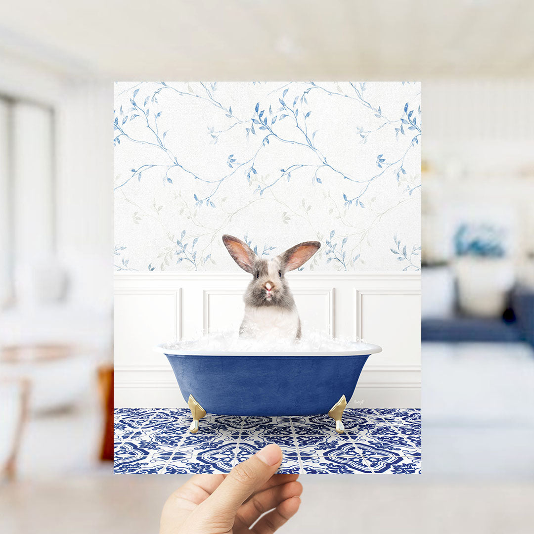A white rabbit sitting in a blue bathtub filled with water, with a floral patterned wall behind it.
