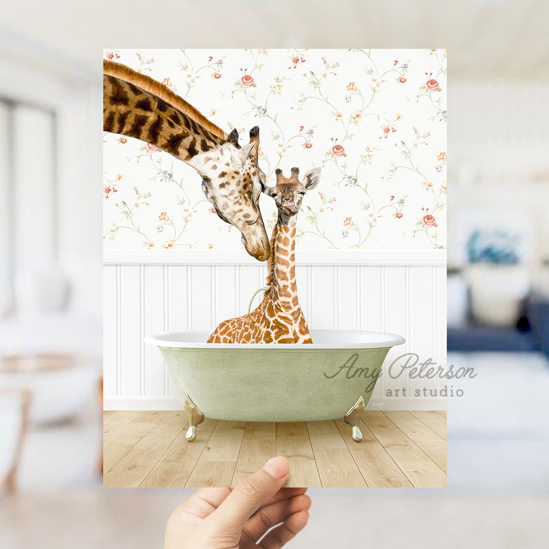 a hand holding up a picture of two giraffes in a bathtub