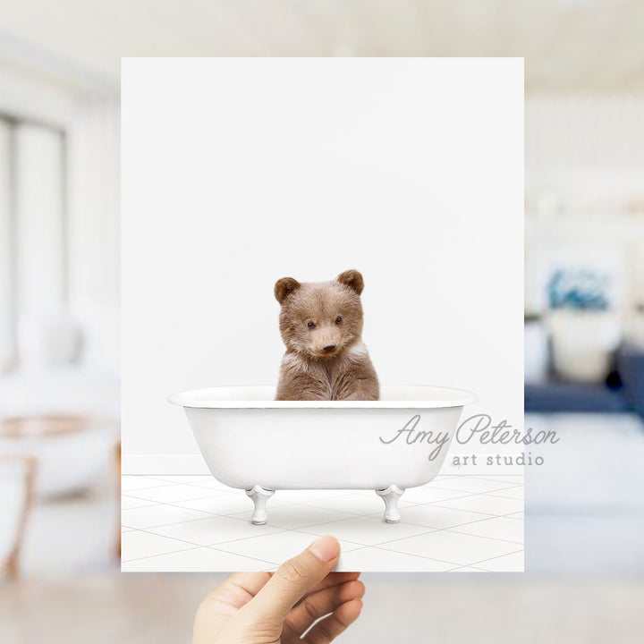 a person holding up a card with a picture of a teddy bear in a bath