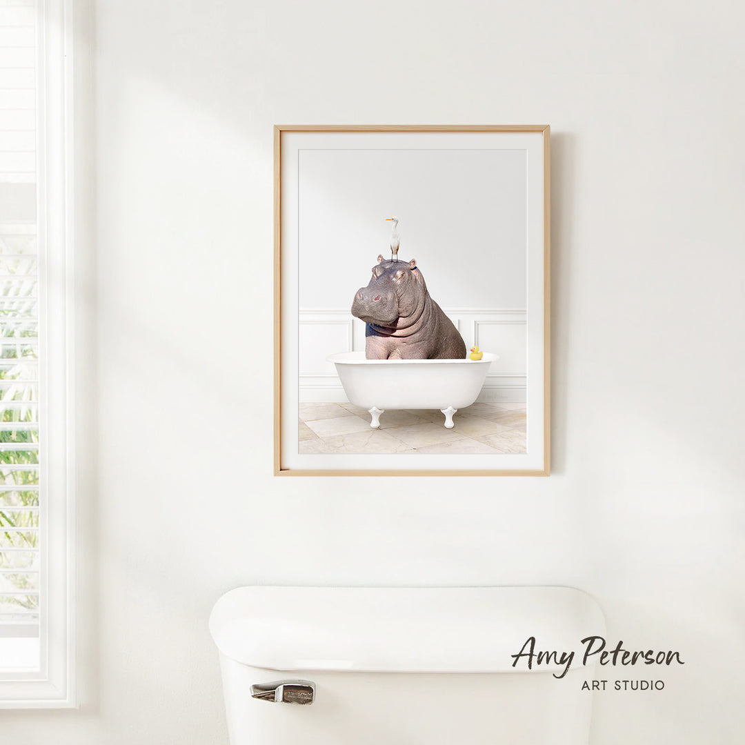A framed image of a hippopotamus sitting in a bathtub, with a yellow rubber duck floating in the water.