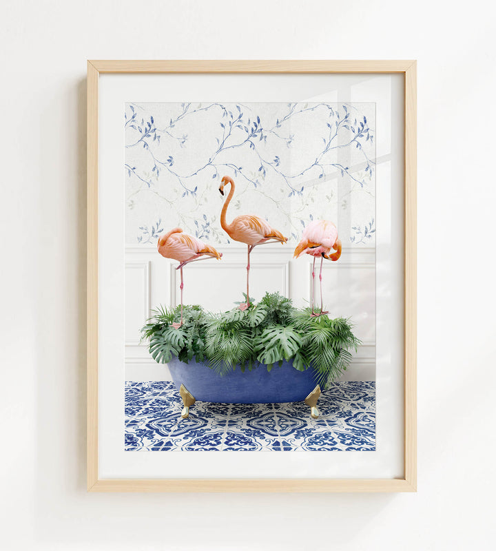 A framed image of three flamingos standing in a blue bathtub filled with green plants, set against a white wall with a blue floral pattern.