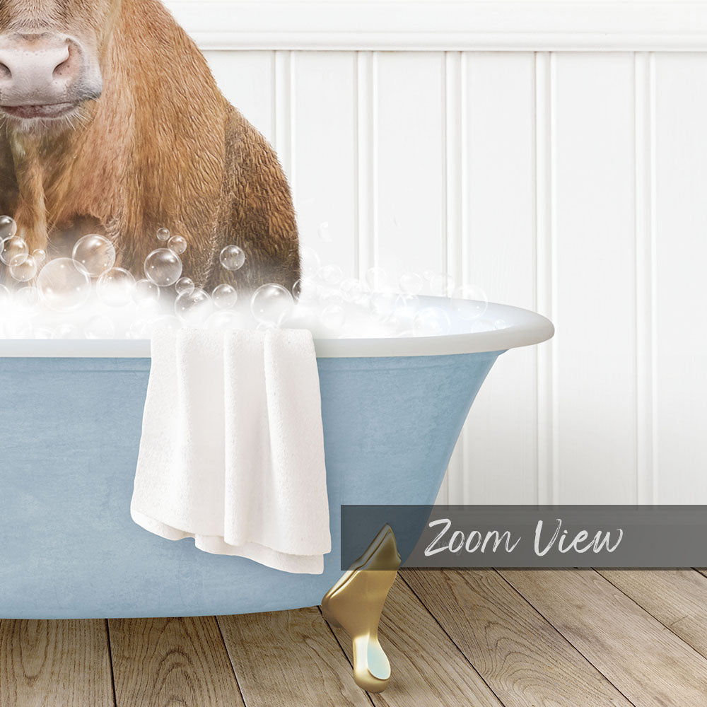 A brown cow is sitting in a blue bathtub filled with bubbles, with a towel and gold faucet visible.