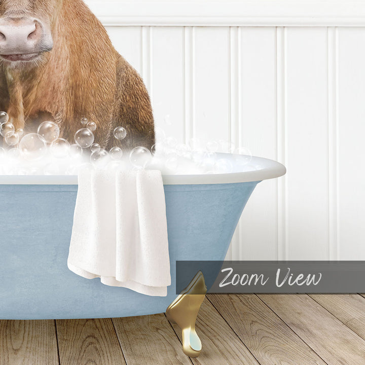 A brown cow is sitting in a blue bathtub filled with bubbles, with a towel and gold faucet visible.