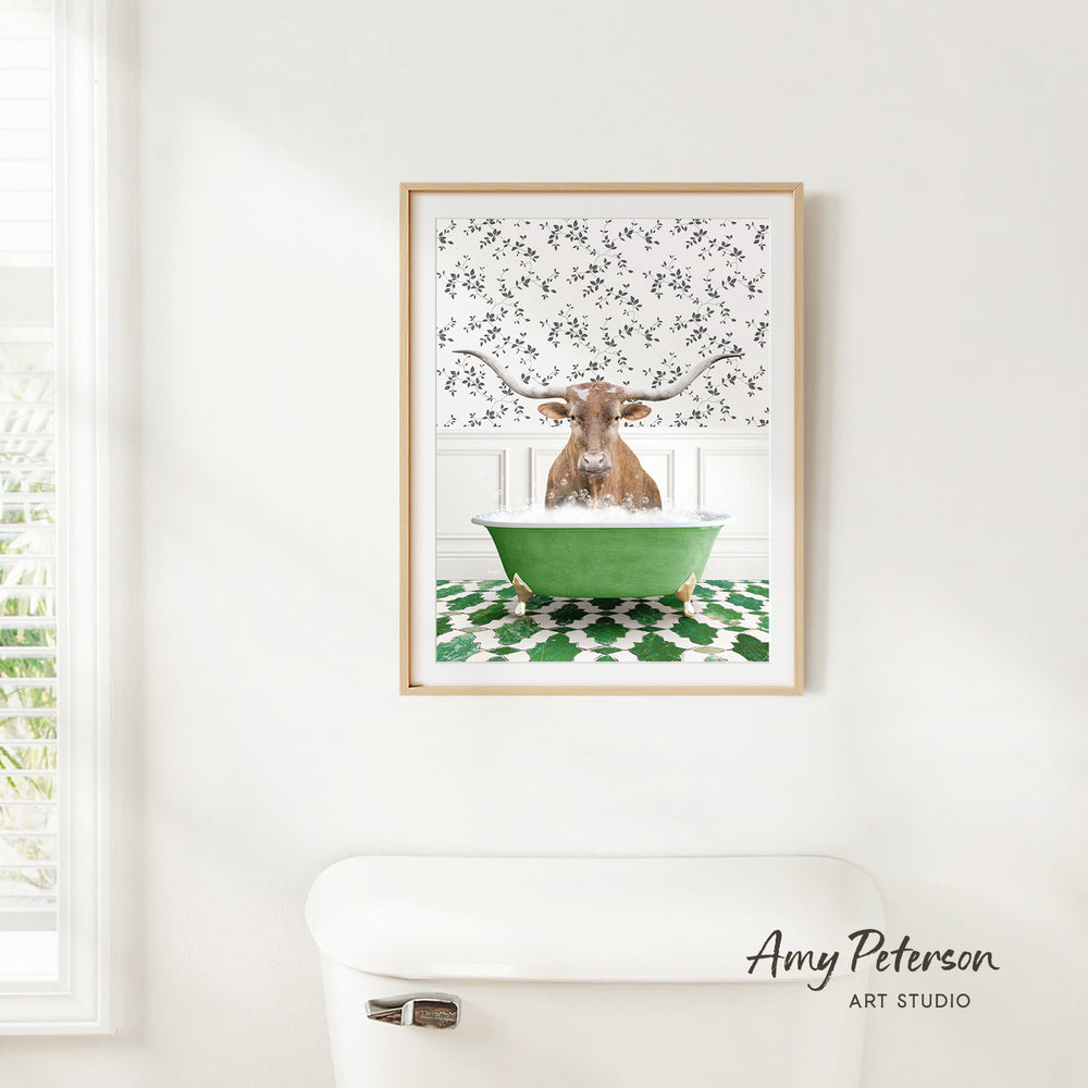 A framed image of a bull with horns sitting in a green bathtub, surrounded by a patterned wall and a white toilet.