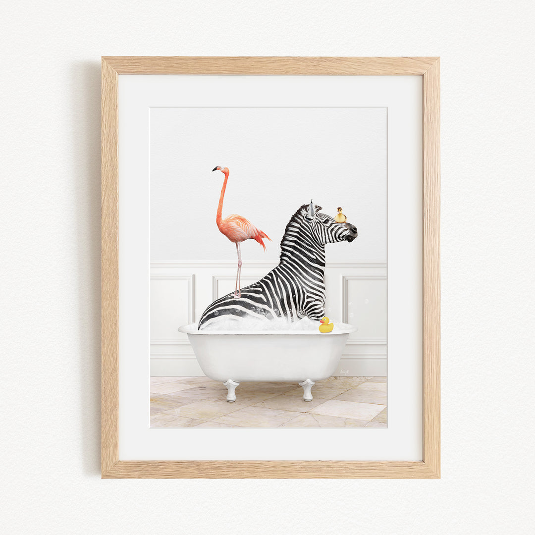 A framed image depicting a zebra sitting in a bathtub, with a flamingo standing on its back and a yellow rubber duck floating nearby.