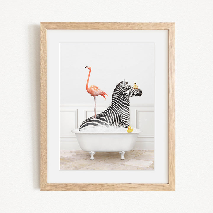 A framed image depicting a zebra sitting in a bathtub, with a flamingo standing on its back and a yellow rubber duck floating nearby.