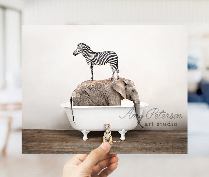 a person holding up a picture of a zebra and an elephant in a bathtub