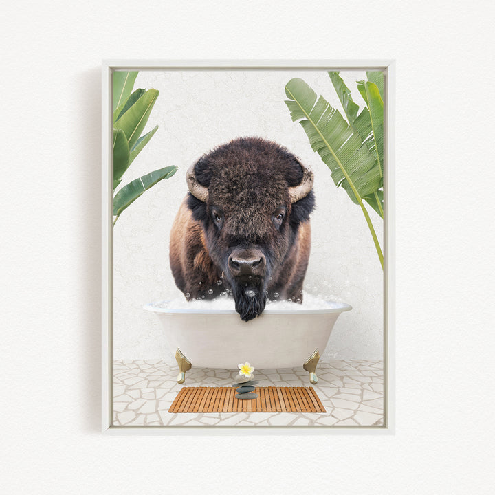 A buffalo is sitting in a bathtub filled with water, surrounded by green leaves and a wooden mat on the floor.