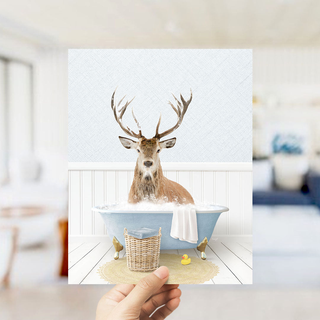 A deer with antlers is sitting in a bathtub filled with water, surrounded by a yellow rubber duck and a wicker basket.