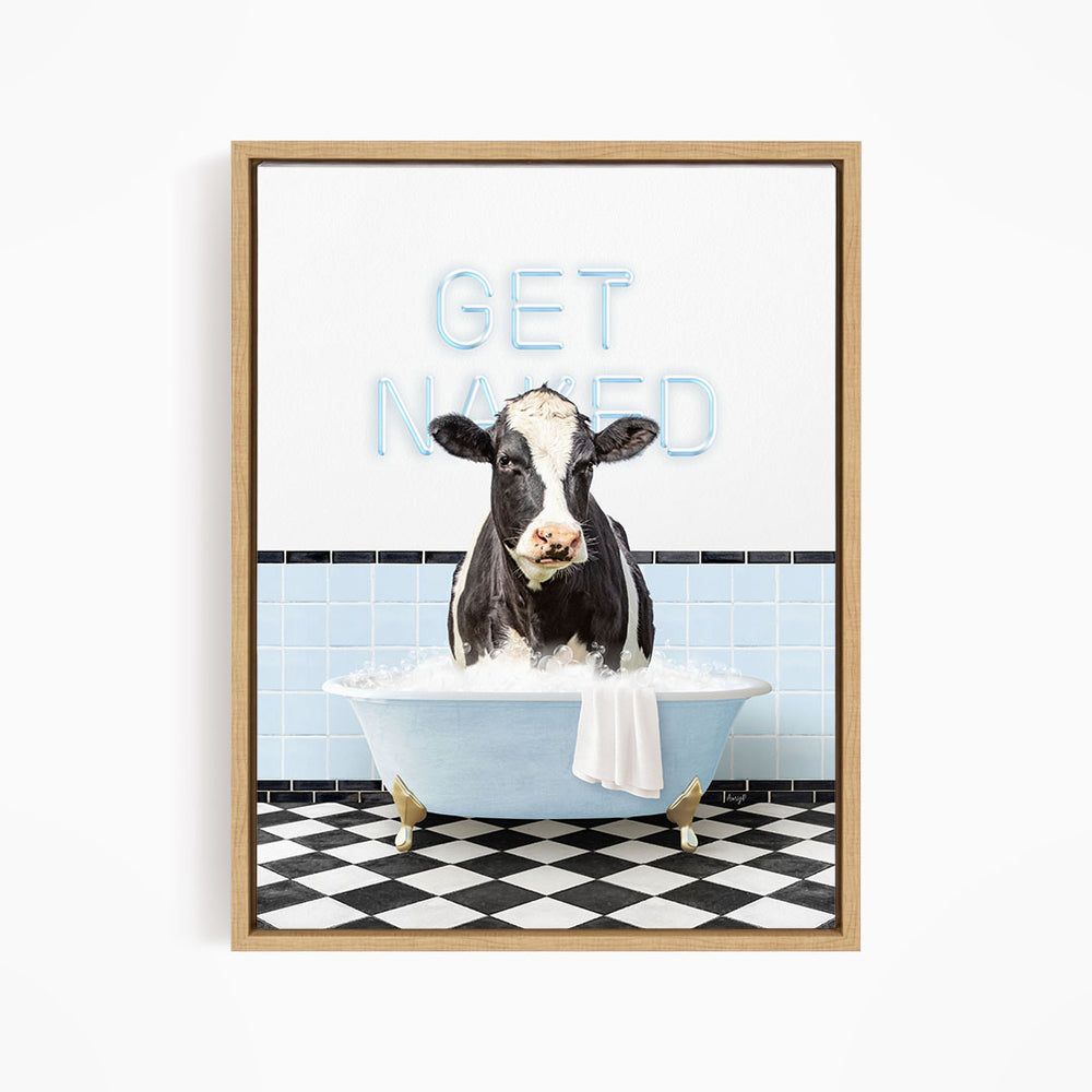 A black and white cow sitting in a bathtub filled with water, with the words "GET NAKED" written on the wall behind it.
