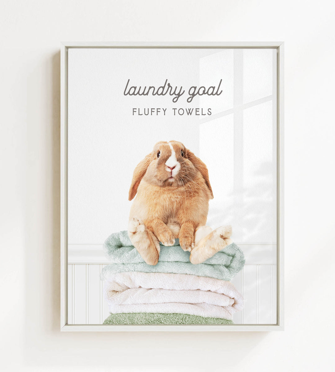 A fluffy rabbit sitting on a stack of towels, with the text "laundry goal" and "FLUFFY TOWELS" displayed above the image.