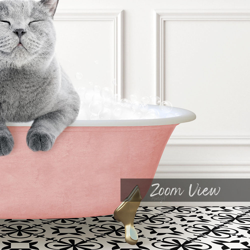 A gray cat sitting in a pink bathtub filled with bubbles, with a gold faucet and a black and white patterned floor in the background.