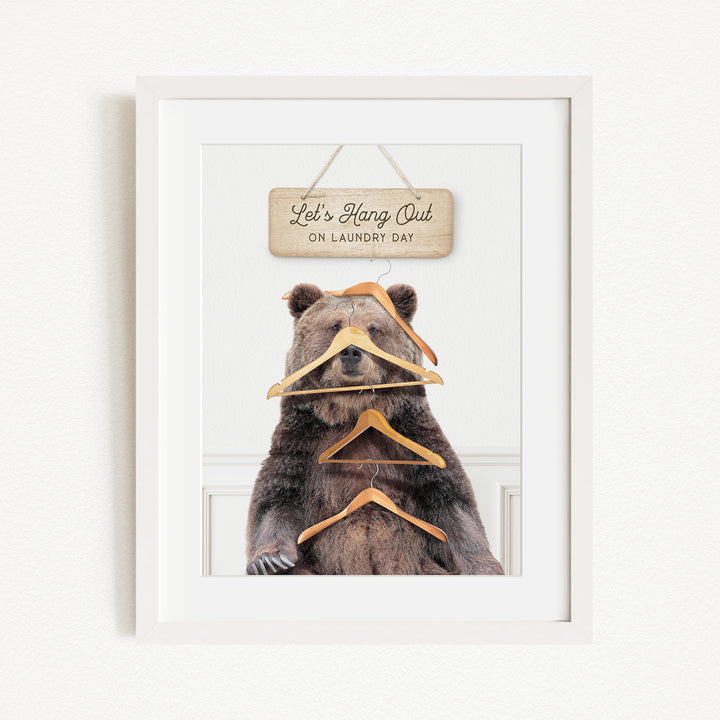 A framed image of a bear sitting in front of a sign that says "Let's Hang Out on Laundry Day".