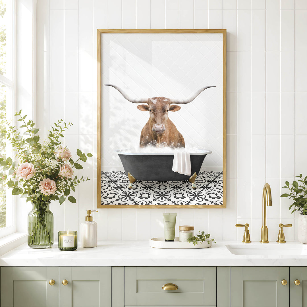 a framed picture of a bull with long horns sitting in a bathtub, surrounded by flowers and candles, with a white tiled wall and a sink in the background.