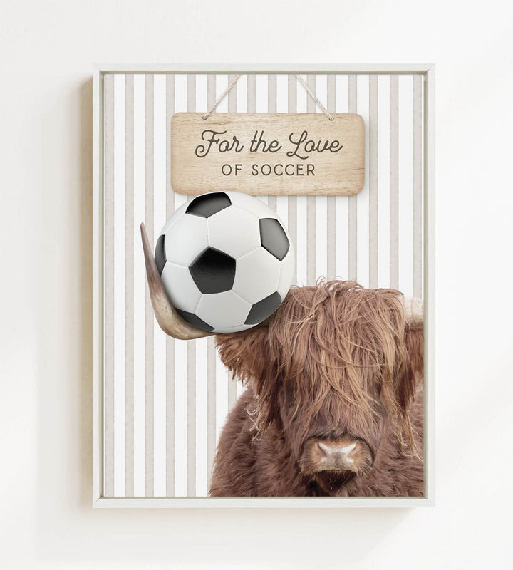 A framed image featuring a brown cow with a soccer ball on its head, with a wooden sign above that says "For the Love of Soccer".