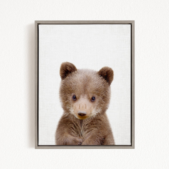A cute baby bear with large eyes and a small nose is the focus of the image.