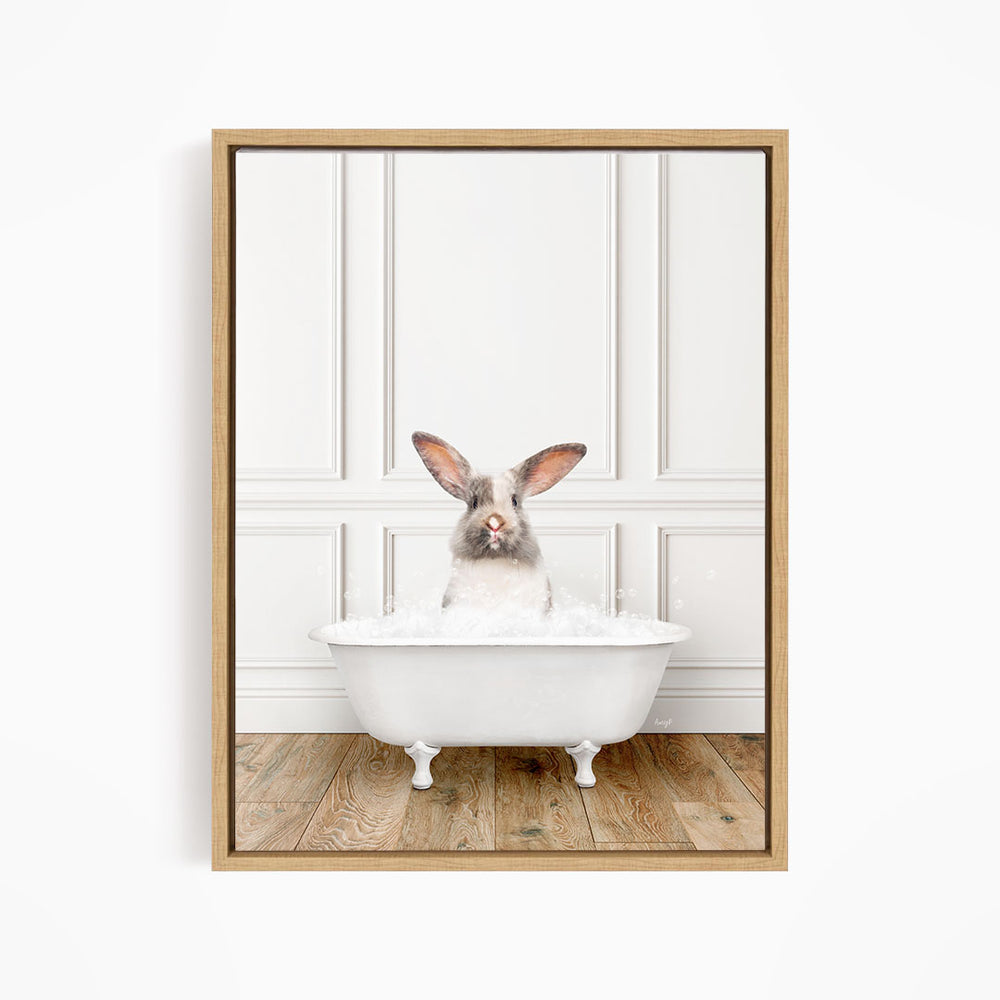 A white rabbit sitting in a white bathtub filled with bubbles, looking directly at the camera.