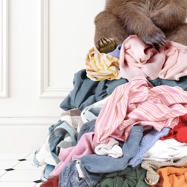 a brown bear sitting on top of a pile of clothes