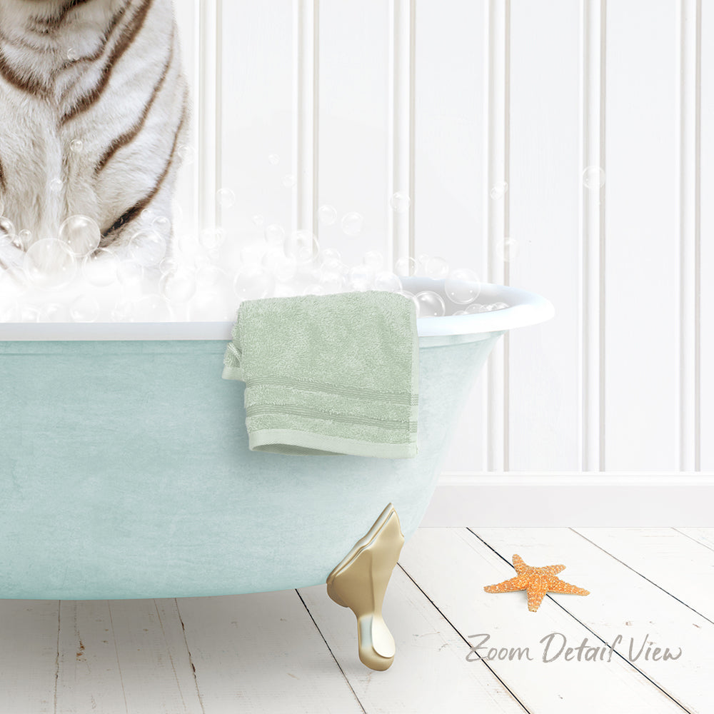 A white cat is sitting in a light blue bathtub filled with bubbles, with a green towel hanging on the side and a starfish on the floor.