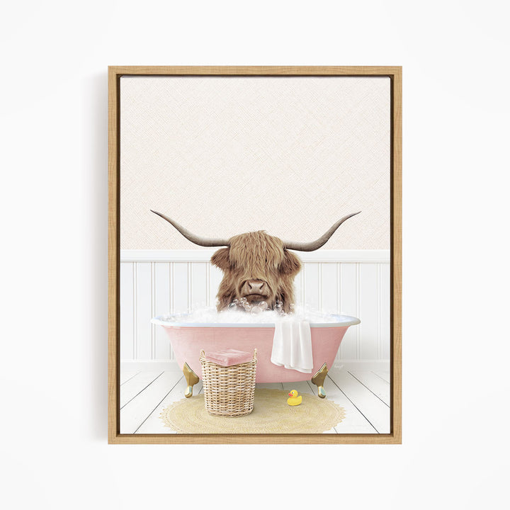 A brown cow with long horns is sitting in a pink bathtub filled with water, surrounded by a yellow rubber duck and a wicker basket.