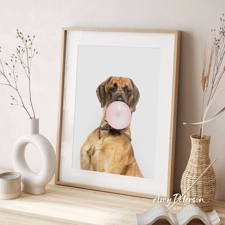 A framed photograph of a dog holding a pink bubble gum bubble in its mouth, placed on a wooden surface next to decorative vases.