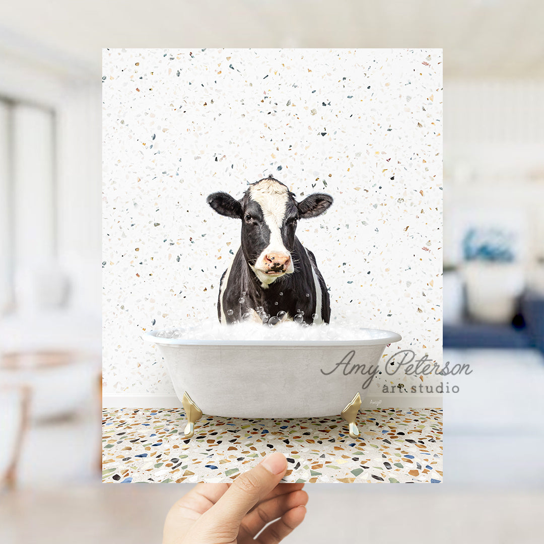 a hand holding up a card with a picture of a cow in a bathtub