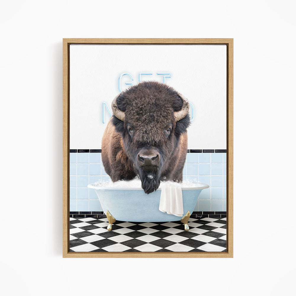 A buffalo with large horns is sitting in a bathtub filled with water, with a towel hanging over the side of the tub.